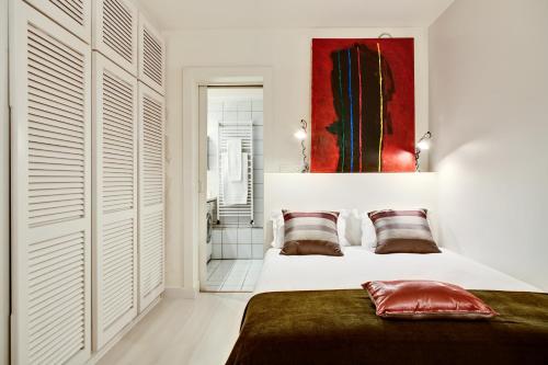 - une chambre avec un lit et une peinture rouge sur le mur dans l'établissement Jardin des Rosiers résidence, à Paris