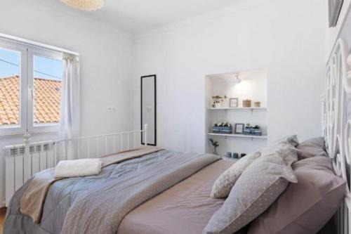 a large bed in a white room with a window at Lomba House, Almoçageme in Colares