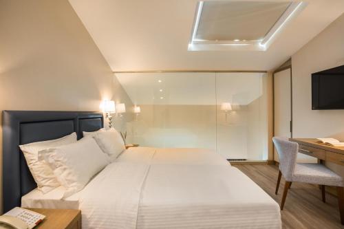 a bedroom with a bed and a desk and a television at Electra Kefalonia Hotel & Spa in Svoronata