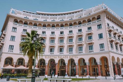 a large white building with a palm tree in front of it at Electra Palace Thessaloniki in Thessaloniki