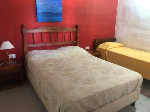 a bedroom with two beds and a red wall at Complejo La Morena in Mina Clavero