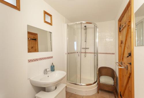 a white bathroom with a shower and a sink at Putham Barn Cutcombe in Wheddon Cross