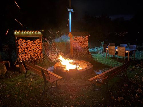 a fire pit in a yard at night with two benches at Przygórze - dom w Górach Sowich in Przygórze