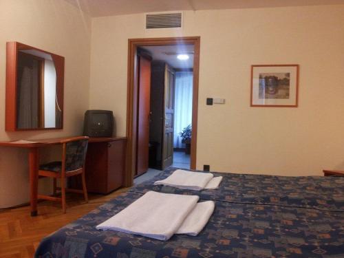 a hotel room with a bed with towels on it at Fenyves Hotel Békéscsaba in Békéscsaba