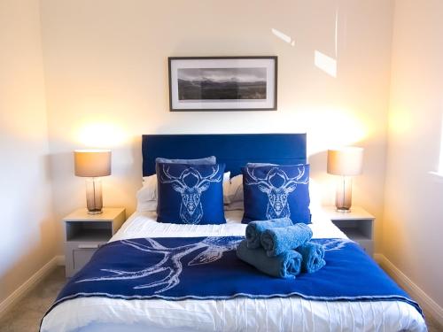a bedroom with a blue bed with two lamps at 26 Ben Avon in Aviemore