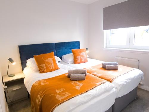 a bedroom with two beds with orange pillows at 26 Ben Avon in Aviemore
