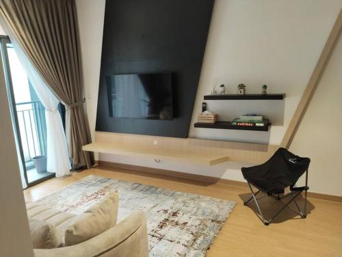 バンティングにあるIman RestHouse at Bandar Gamuda Coveのリビングルーム(テレビ、椅子付)