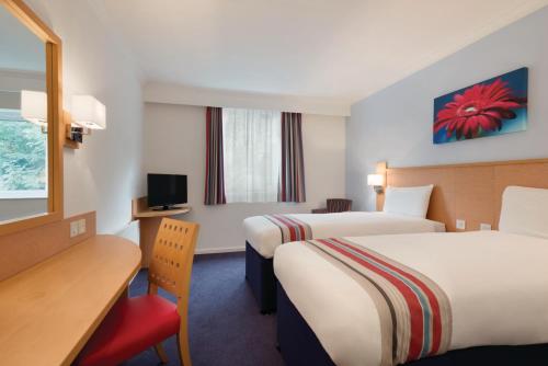 a hotel room with two beds and a desk at Ramada Wakefield in Wakefield