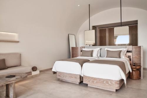 two beds in a bedroom with a couch and a mirror at Canaves Epitome - Small Luxury Hotels of the World in Oia