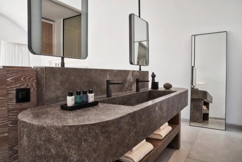 a bathroom with a large concrete sink and mirrors at Canaves Epitome - Small Luxury Hotels of the World in Oia