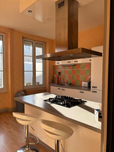 - une cuisine avec une cuisinière et un comptoir avec des tabourets dans l'établissement Appartement pour 5 à 7 personnes, à Chef-Boutonne
