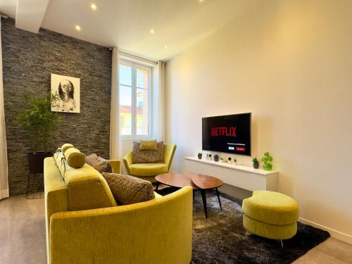 d'un salon avec des chaises jaunes et une télévision. dans l'établissement Eleganza By SCLS Locations, à Cannes