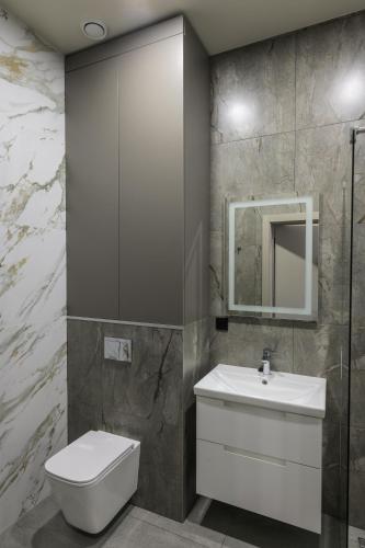 a bathroom with a toilet and a sink and a mirror at REST INN apart hotel in Cherkasy