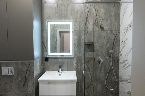 a bathroom with a sink and a shower with a mirror at REST INN apart hotel in Cherkasy