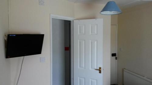 Habitación con puerta y TV en la pared en The White Hart Inn, en Tetford