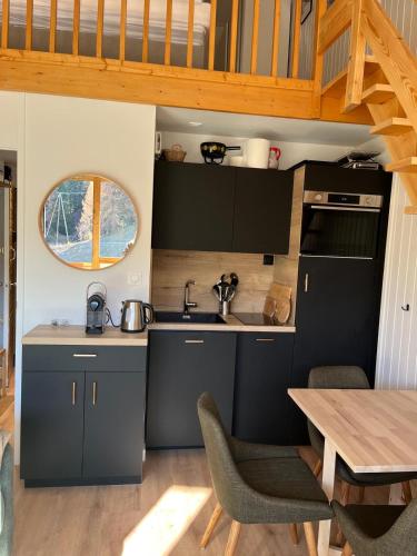 une cuisine avec des armoires noires et une table en bois dans l'établissement Appt Plagne Villages skis aux pieds - LES HAMEAUX 2, à Plagne Villages