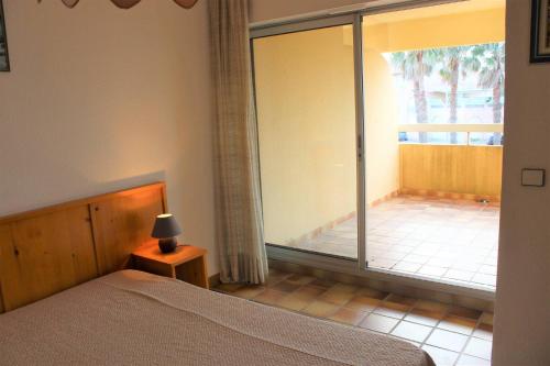 - une chambre avec un lit et une grande porte coulissante en verre dans l'établissement Zénitude pour ce bien en front de mer avec parking privatif - 4LAG502, à Saint Cyprien Plage