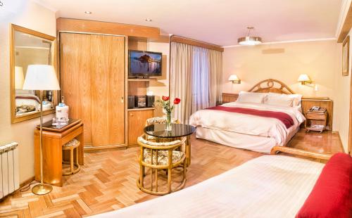 サン・カルロス・デ・バリローチェにあるホテル クリスタルのベッドとテーブルが備わるホテルルームです。