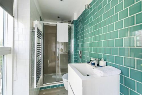 a bathroom with a sink and a toilet and green tiles at Split Level 3 Bedroom Top Floor Flat in London