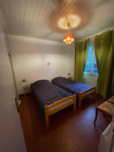 - une chambre avec 2 lits et des rideaux verts dans l'établissement Ma Briane - Plage à 150 m, à La Tranche-sur-Mer