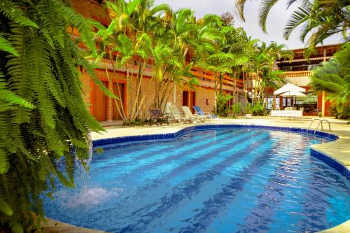 una piscina en un complejo con palmeras en Hotel Dellamares, en Ubatuba