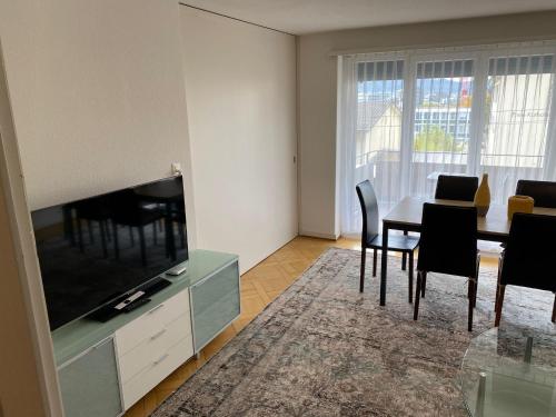 Una sala de estar con una mesa de comedor y un televisor. en 2BR near city center - Vineyard 21, en Zúrich