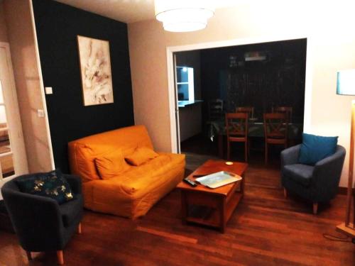 a living room with an orange couch and a table at LA TANIÈRE in Gueures