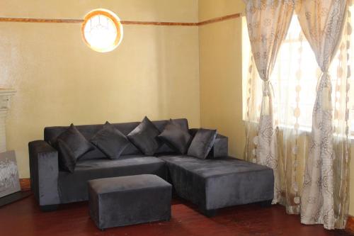 a living room with a black couch and a window at Self-catering rooms Florida in Roodepoort