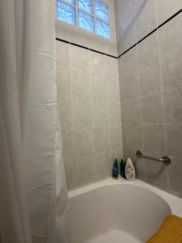 La salle de bains est pourvue d'une baignoire blanche et d'une fenêtre. dans l'établissement Appartement parisien, à Paris