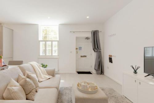 a white living room with a couch and a tv at Elegant Epsom Family in Epsom