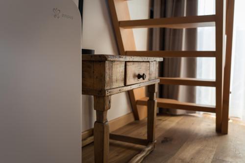 a wooden table and a chair next to a ladder at Green Hotel Genzianella in Roncone