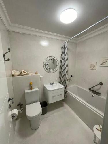 a white bathroom with a toilet and a bath tub at Dasseneiland Apartment Yzerfontein in Yzerfontein