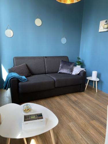 un salon avec un canapé noir et une table dans l'établissement Marianne 4, à Bergerac