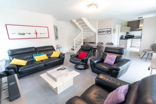 Il comprend un salon doté d'un mobilier en cuir noir et d'un escalier. dans l'établissement Ti Anna, à Carnac