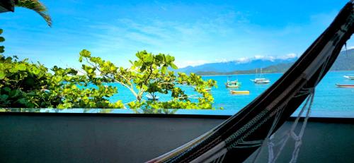 a hammock with a view of the water and boats at Pousada Sobre As Ondas de Picinguaba in Picinguaba