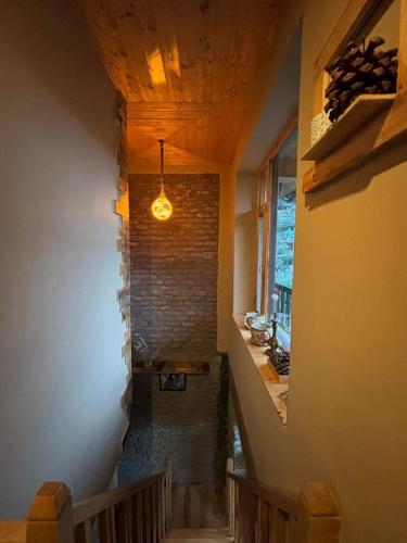 a hallway with a staircase with a brick wall at Rustic Roots Home Stay in Nagar