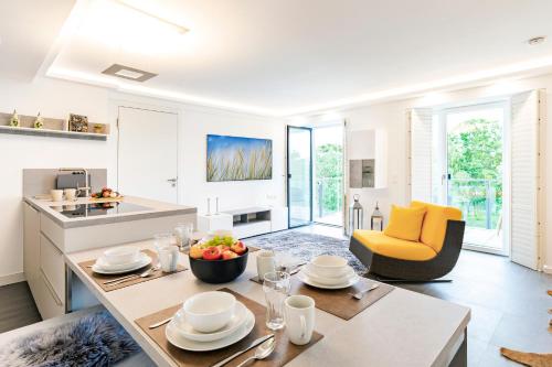 eine Küche und ein Wohnzimmer mit einem Tisch und einem gelben Stuhl in der Unterkunft FeWo Prora - GiGi in Binz