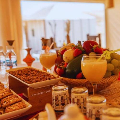a table with a bunch of food and drinks at Merzouga Horizon Luxury Camp in Merzouga