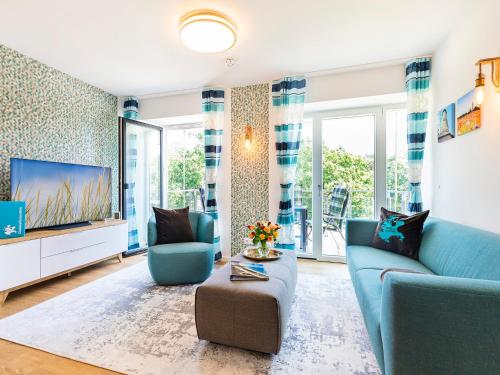 ein Wohnzimmer mit einem blauen Sofa und einem Fernseher in der Unterkunft FeWo Prora - PRORA week in Binz