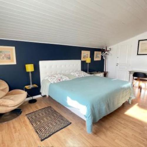 - une chambre avec un lit bleu et une chaise dans l'établissement Chambres d'Hôtes d'Aliénor, à Soulac-sur-Mer