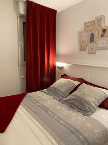 - un lit dans une chambre dotée d'un rideau rouge dans l'établissement F2 cozy vue mer, piscine, parking, tout à pied !, à Antibes