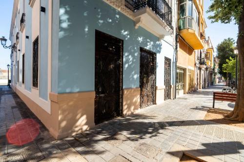 a blue and white building on a street with a bench at VLC HOST - Reina 168 in Valencia