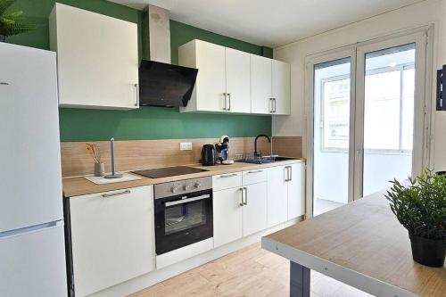 une cuisine avec des armoires blanches et une table à l'intérieur dans l'établissement C'est chez Maurice! 4 ch WIFI balcon parking free, à Saint-Étienne