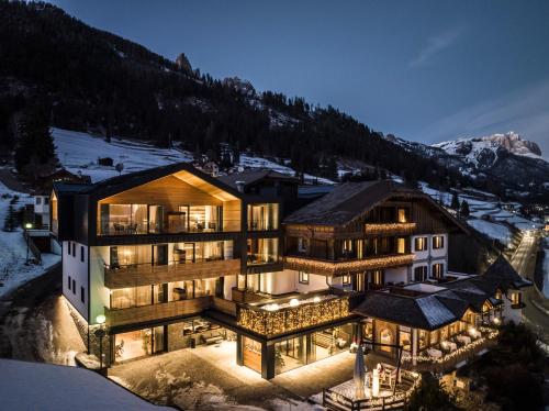 a house in the mountains with its lights on at Ladinia Dolomites View - Adults Only in Pozza di Fassa