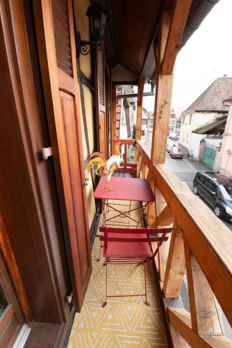 - un balcon avec deux chaises rouges et une table dans l'établissement S'Hüsli - Maison vigneronne au coeur du vignoble, à Bergheim