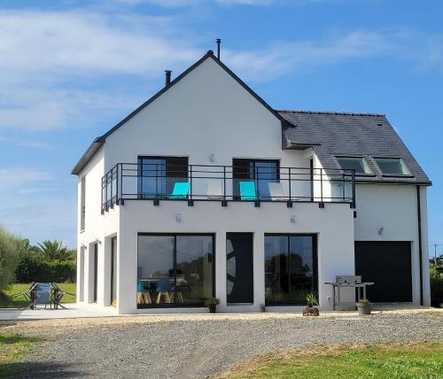 a white house with a balcony on top of it at Villa l'estran récente vue mer Plounéour-Brignogan-plages in Plounéour-Trez