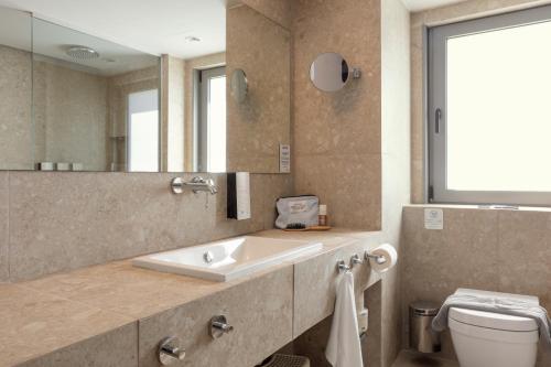 a bathroom with a sink and a toilet and a mirror at SUNWING Sandy Bay Beach Village in Ayia Napa