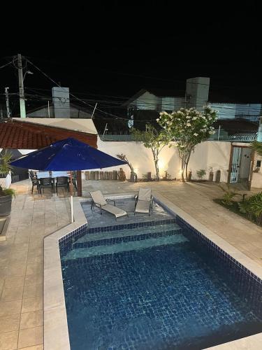 a swimming pool with chairs and a blue umbrella at Residence Dunas Exclusive in Natal