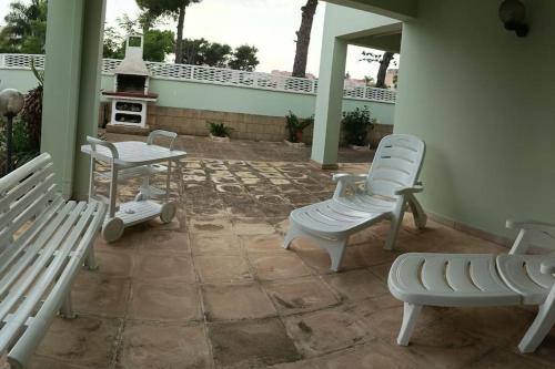 a patio with two white chairs and a stove at Villa Valchiria in Campomarino
