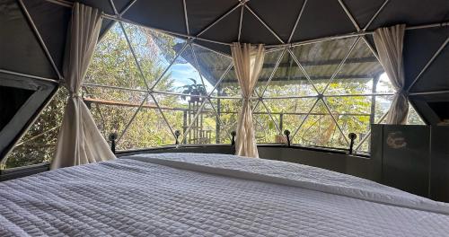 a bedroom with a large window with a bed in it at Omghat Glamping - Domo Sarasvasti in El Peñol